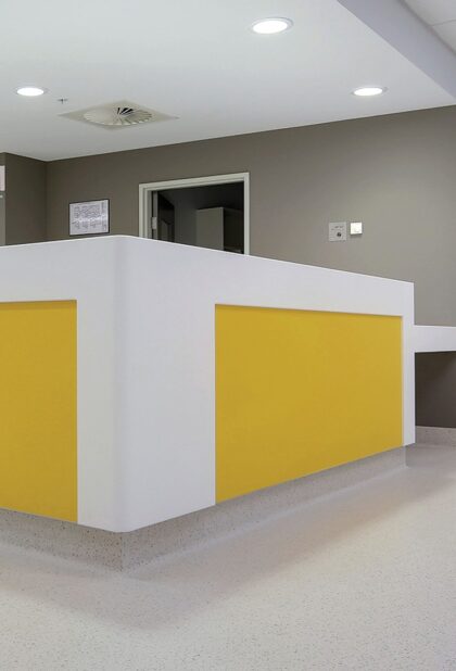 Prestige PUR homogeneous vinyl flooring in pale grey around a yellow reception desk